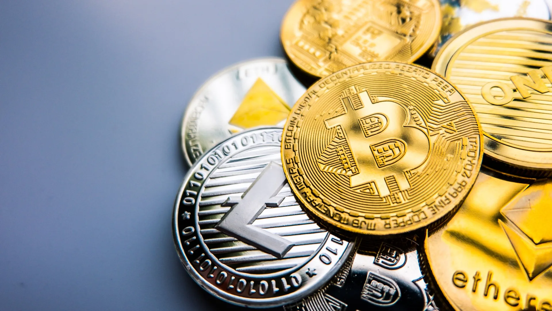 Gold and silver cryptocurrency coins, with a Bitcoin coin in the centre.