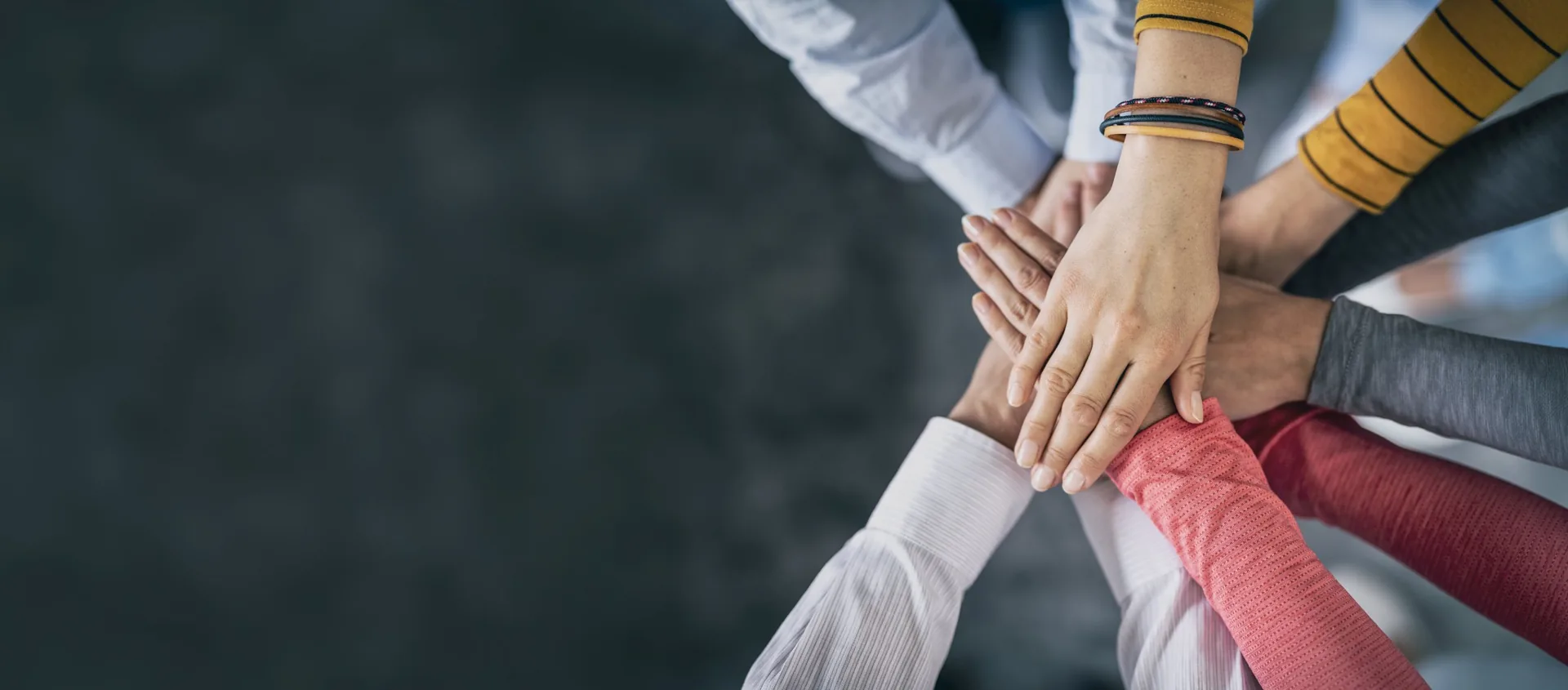 Hands of several people stacked together in the middle of a circle.