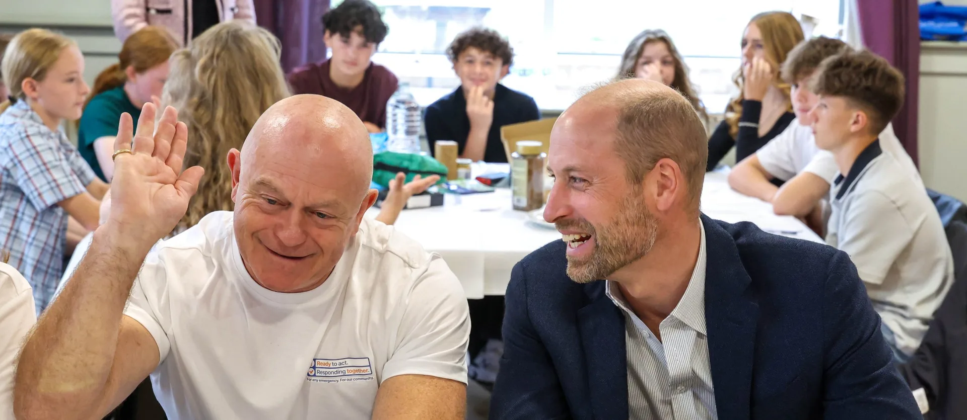HRH, Prince William, The Prince of Wales, laughing with our ambassador Ross Kemp at a table of young people.