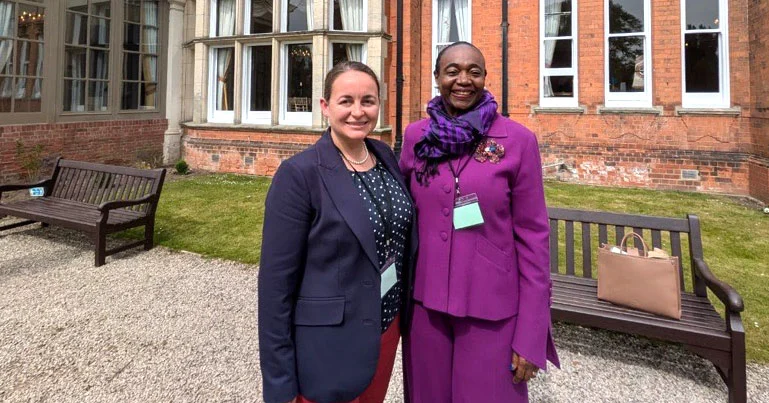 Thelma Stober and Mhairi Sharp standing together outside a red-brick building.